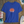 Blue t-shirt with a sun graphic and text on a wooden surface