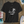 Black t-shirt with a palm tree design on a wooden surface