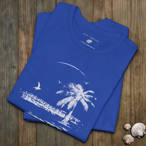 Blue t-shirt with a palm tree and beach design on a wooden surface