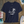 Navy blue t-shirt with a white palm tree design on a wooden surface
